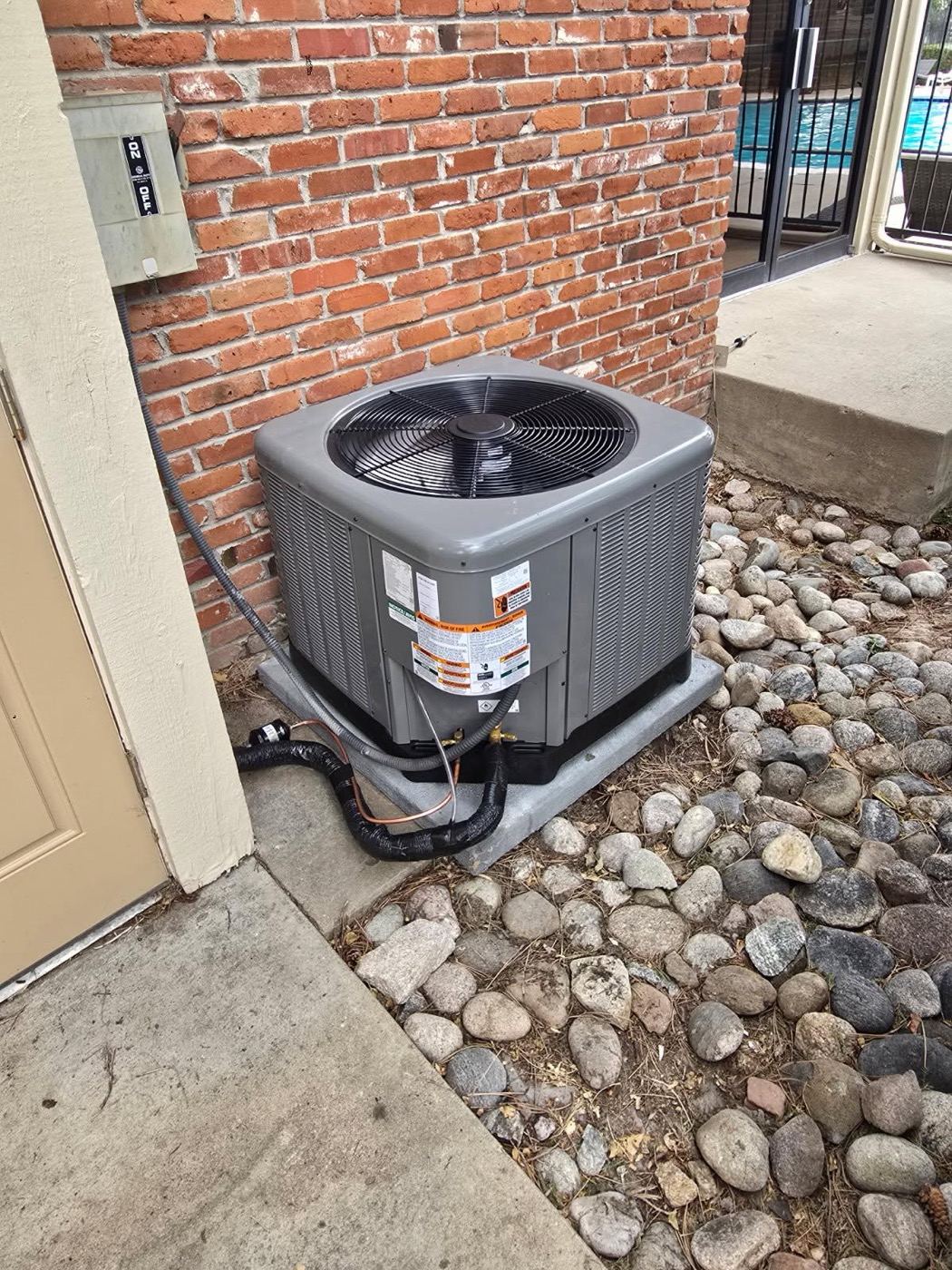 AC replacement: new air conditioner condenser installed on a pad beside a brick building in the south Denver metro