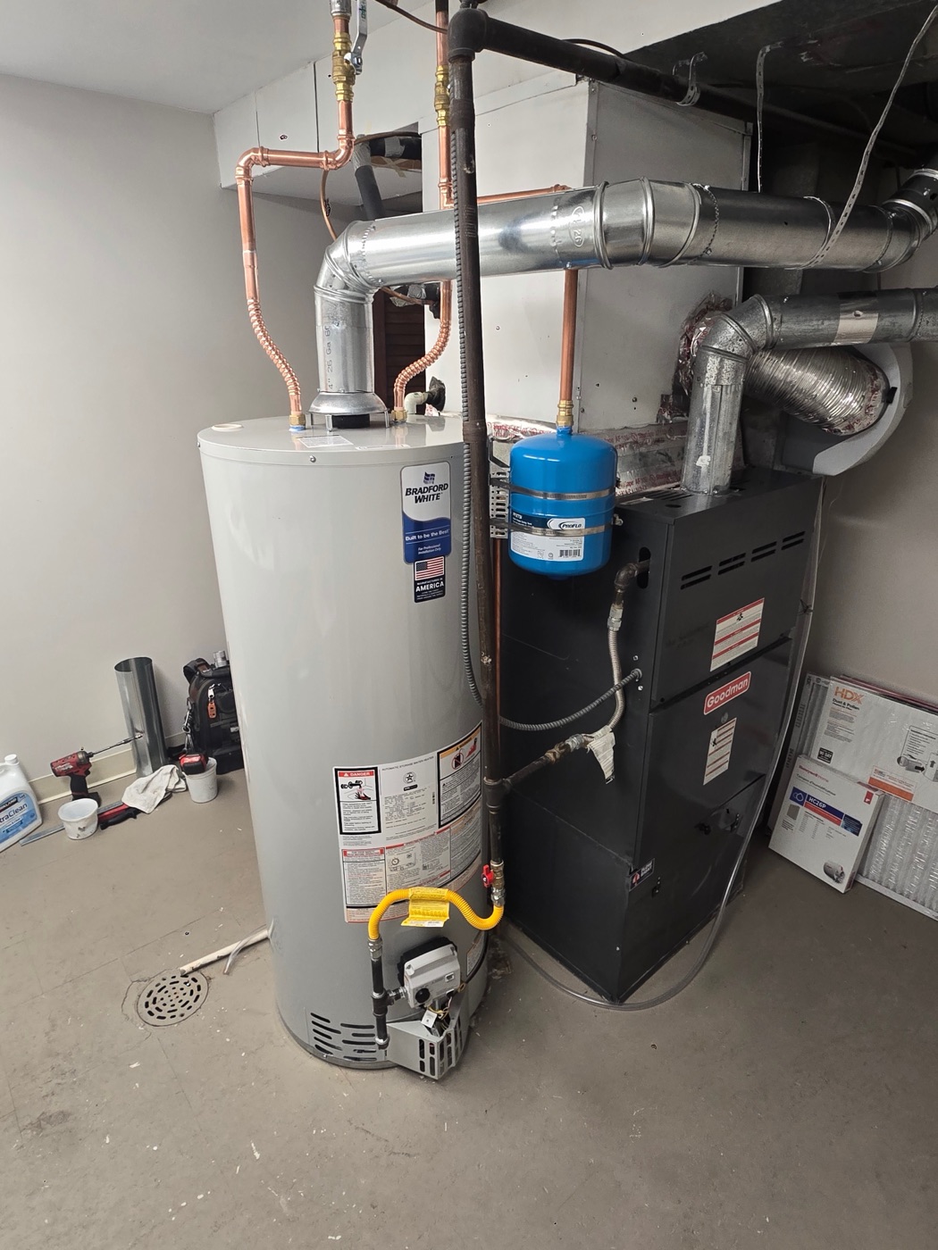 Water heater replacement: new Bradford White gas water heater installed with fresh copper lines, gas line and venting beside a Goodman furnace in a Colorado home